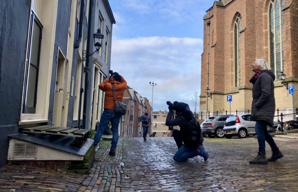 Deelnemers van de Fotowolk maken via de reflectie in het raam een foto van de Stevenskerk