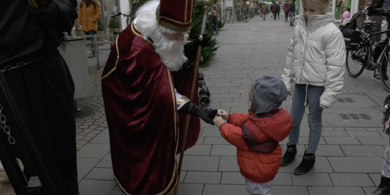 De Duitse Sint geeft chocola aan kinderen die voor hem zingen